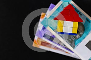 Top close up shot of a toy house on money notes placed over black background