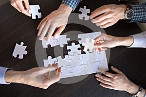 Top close up view of hands engaged in assembling puzzle