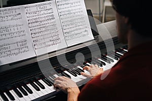 Top close-up view of hands of unrecognizable musician man playing on piano at home.