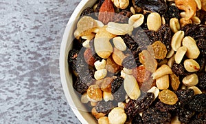 Top close view of a bowl filled with high energy trail mix on a gray mottled background in natural light