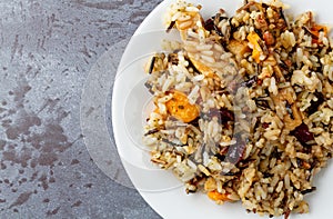 Top close view of chicken with pecans and wild rice on a plate atop a gray background