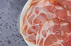 Top close view of a plate of dry coppa on a gray mottled tabletop photo