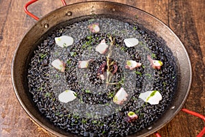 Top closeup of Arros Negre in a black pot on the wooden background