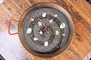 Top closeup of Arros Negre in a black pot on the wooden background photo