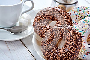 Top Closeup photo of sweet breakfast or snacks. Chocolate and vanilla donuts and cup of black coffee