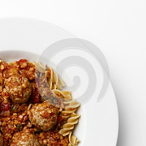 Top corner of a plate of Meatballs in a tomato sause with paste