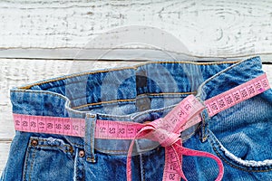 Top of denim trousers, on a wooden background. jeans with a measuring tape