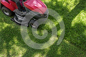 Top down above view of professional lawn mower worker cutting fresh green grass with landcaping tractor equipment