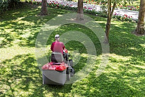 Top down above view of professional lawn mower worker cutting fresh green grass with landcaping tractor equipment