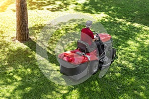 Top down above view of professional lawn mower worker cutting fresh green grass with landcaping tractor equipment