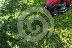 Top down above view of professional lawn mower worker cutting fresh green grass with landcaping tractor equipment