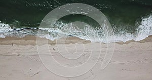 Top down aerial shot of foamy green waves of half moon bay beach pan right