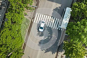 Top down aerial view of busy street with moving cars traffic and zebra road pedestrian crosswalk