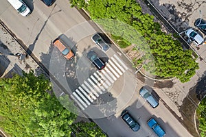 Top down aerial view of busy street with moving cars traffic and zebra road pedestrian crosswalk