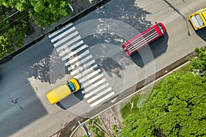 Top down aerial view of busy street with moving cars traffic and zebra road pedestrian crosswalk