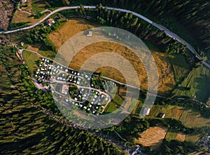 Top down aerial view of a camping site, recreation with a tent and parking for a motor home, camper van, harvested field,