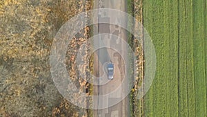 Top down aerial view of a car driving fast on bad road with potholes.