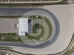 Top down aerial view of curve in motor sport race track circuit with sand roadside