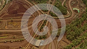 Top down aerial view of dump trucks and diggers working hard on a nickel mining site in Taganito Philippines.