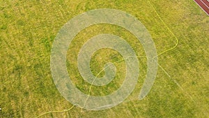 Top down aerial view of football field surface covered with green grass and sprinklers spraying water.