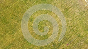 Top down aerial view of football field surface covered with green grass and sprinklers spraying water.