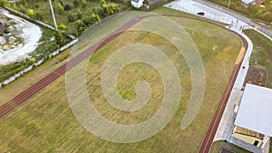 Top down aerial view of football field surface covered with green grass and sprinklers spraying water.