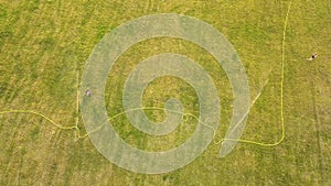 Top down aerial view of football field surface covered with green grass and sprinklers spraying water.