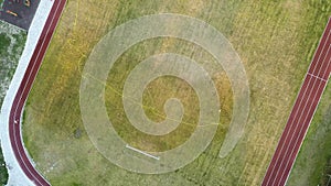 Top down aerial view of football field surface covered with green grass and sprinklers spraying water.