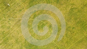 Top down aerial view of football field surface covered with green grass and sprinklers spraying water.Top down aerial view of foot