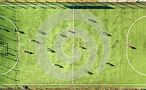 Top down aerial view of green football sports field and players playing football. Drone taken image of small unrecognizable