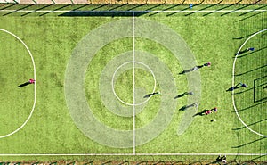 Top down aerial view of green football sports field and players playing football. Drone taken image of small unrecognizable