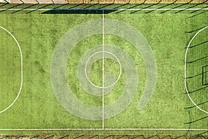 Top down aerial view of green football sports field and players playing football. Drone taken image of small unrecognizable