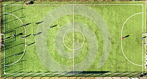 Top down aerial view of green football sports field and players playing football. Drone taken image of small unrecognizable