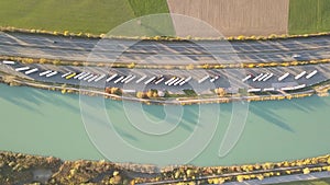 Top down aerial view of highway interstate road with fast moving traffic and parking lot with parked lorry trucks.