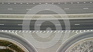 Top down aerial view of new highway high speed road intersections with few vehicles moving in the morning.