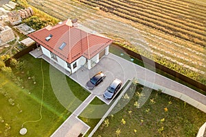 Top down aerial view of a private house with red tiled roof and spacious yard with parked two new cars