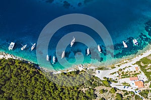 Top down aerial view of sailing boats docked in blue bay of Fiskardo, Kefalonia island, Ionian, Greece