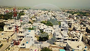 Top down aerial view of small houses in suuny wearther with grassy fields and roads , traffic. Camera is raising up over bulidings