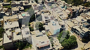 Top down aerial view of small houses in suuny wearther with grassy fields and roads , traffic. Camera is raising up over bulidings