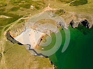 Top down aerial view of a tiny sandy beach and cove in West Wales Pembrokeshire