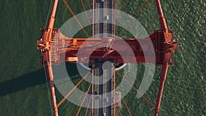 Top down ascending footage of massive red steel construction of famous Golden Gate Bridge. Vehicles driving on multilane