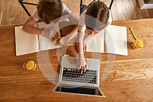 Top down children study online on computer together