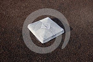 Top down, close up view of a base on a clean baseball field on a bright, sunny day
