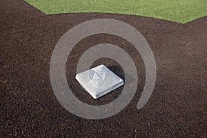 Top down, close up view of a base on a clean baseball field on a bright, sunny day