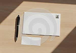 Top-down composition of envelope, stamp, pen, and mailing label on office desk surface in daylight, sharp and minimal design