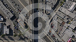 Top down descending footage of busy road intersection under railway bridge in city. Los Angeles, California, USA