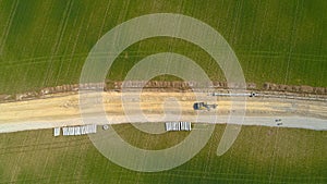 TOP DOWN: Flying above road under construction with heavy machinery and workers.