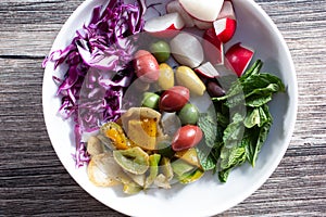 top down Mediterranean veggie medley plate, salad, olive, cabbage, radish, mint