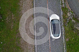 TOP DOWN: Modern white car cruises along empty cobblestone road in Switzerland.