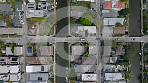 Top down panning footage of cars slowly moving on street in residential urban borough with water canals. Los Angeles